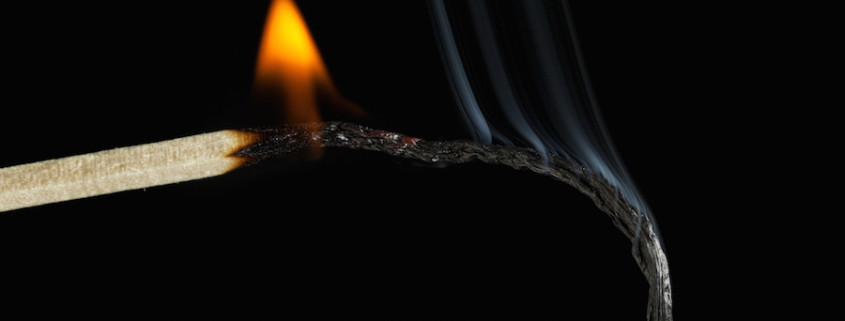 Burnout concept. Closeup of burning match, black background.