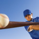 Baseball player hitting the ball with a bat against clear blue sky