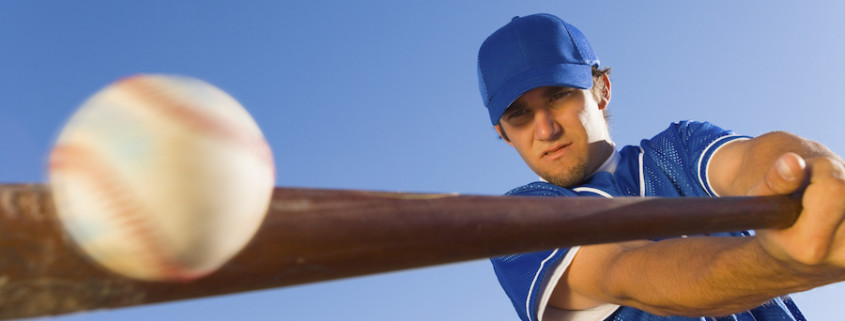 Baseball player hitting the ball with a bat against clear blue sky