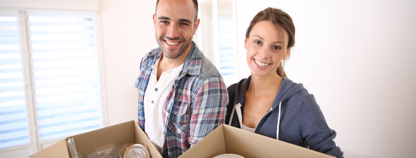 Cheerful young adults packing their stuff in cardboards