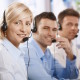 Happy young customer service operators talking on headset, looking at camera, smiling.